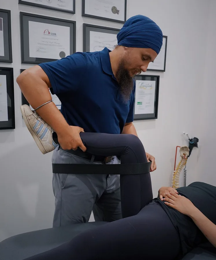 Physiotherapist stretching a patient's hip with a strap