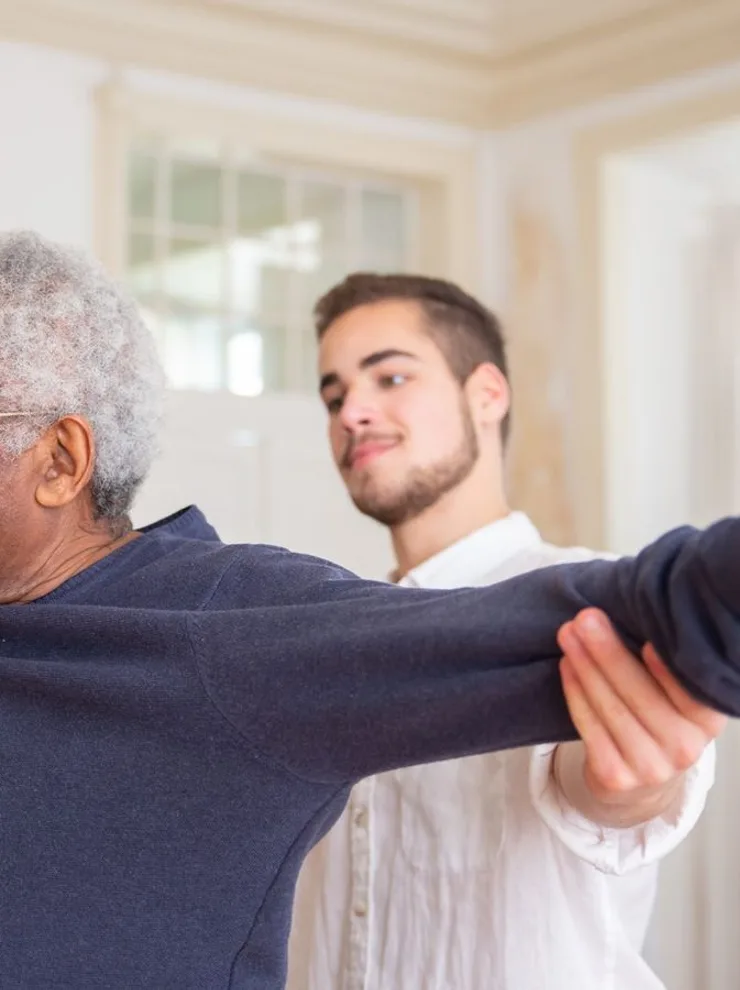 Physiotherapist helping an older man with an arm stretch