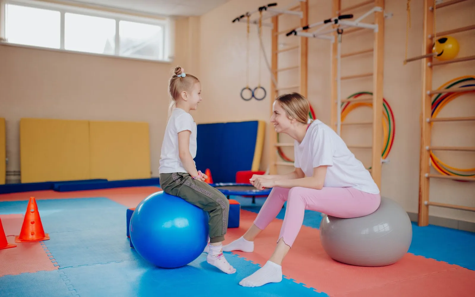 Therapist and a young girl doing a balance exercise on therapy balls